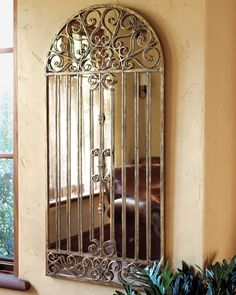 a mirror that is on the wall in front of a plant and potted plants