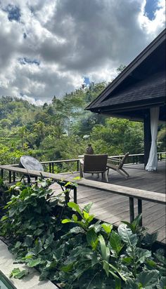 a person sitting at a table on a deck in front of some trees and bushes