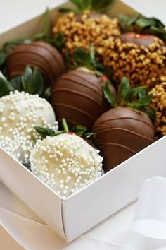 a box filled with chocolate covered strawberries on top of a white table cloth next to a napkin