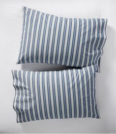 two blue and white striped pillows sitting next to each other