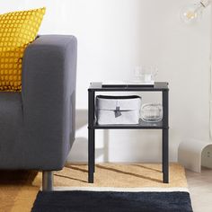 a grey couch sitting next to a table on top of a rug