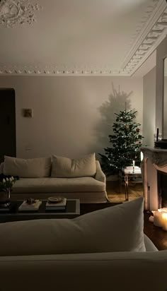 a living room filled with furniture and a christmas tree in front of a fire place