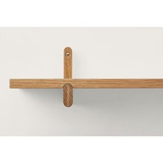 a wooden shelf with two pegs on it and a white wall in the background