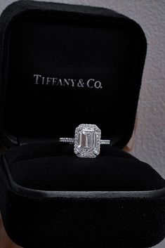 an engagement ring in a black velvet box with the word tiffany & co on it