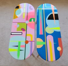 two skateboards are laying on the ground next to each other and one is painted with different colors