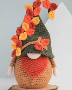 a crocheted gnome hat sitting on top of a piece of wood with orange and yellow flowers