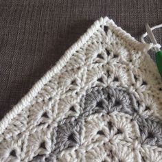 a crochet square with a green needle on it