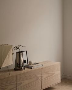 a table with a vase and some books on it next to a wall mounted clock