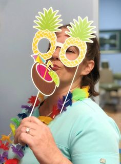 a woman wearing a pineapple mask and holding a pair of eyeglasses in front of her face