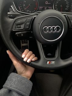 a woman holding the steering wheel of a car with her hand on the steering wheel