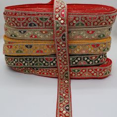 a stack of red and gold ribbons with beaded trimmings on each side