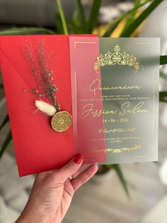 a person holding up a red and gold wedding card