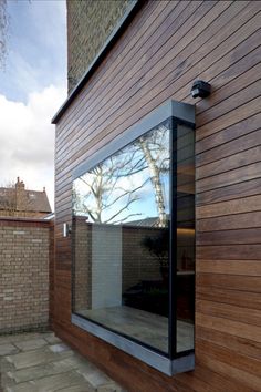 a wooden building with glass windows on the outside and brick walls in front of it