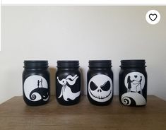 three black and white mason jars with painted designs on them, one has a jack skellingy face