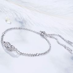 A brilliant way to show her your love is forever, this dainty bracelet will certainly touch her heart. This meaningful design showcases two ribbons interlocked for a infinity symbol-shaped look, while shimmering round stones add eye-catching sparkle to the design. This elegant bracelet makes a stunning statement of everlasting love. A great anytime choice, this fashion bracelet is sure to become an instant favorite. Carat Weight: 0.21 ctStone Size: 1.1 mmNumber of Stones: 21 Stone Shape: RoundSt Elegant Diamond Bracelets For Promise, Elegant Promise Bracelet Jewelry, Diamond Infinity Bracelets For Anniversary, Elegant Infinity Bracelets With Diamond Accents, Elegant Infinity Bracelet With Diamond Accents, Elegant Bracelets With Adjustable Chain For Anniversary, Elegant Adjustable Chain Bracelets For Anniversary, Elegant Silver Diamond Bracelet As Gift, Elegant Adjustable Chain Bracelet For Anniversary