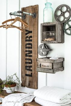 a wooden sign hanging on the side of a wall next to a towel rack and potted plant