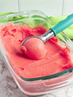 a scoop of ice cream in a glass container with a green spatula next to it