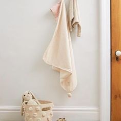 there is a coat rack with two coats hanging on it and a teddy bear next to it