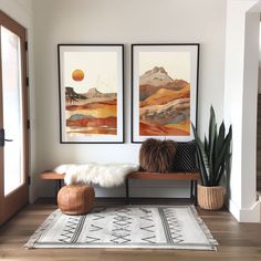 two paintings hang on the wall above a bench in front of a rug and potted plant