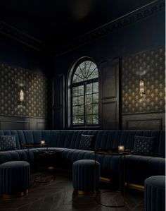 a room with blue velvet couches and round tables in front of a large window