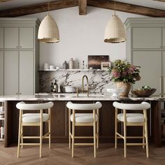 a kitchen with marble counter tops and stools in front of an island topped with flowers