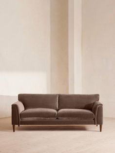 a brown couch sitting on top of a hard wood floor next to a white wall