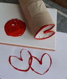 a roll of toilet paper sitting on top of a piece of paper next to a red heart stamp