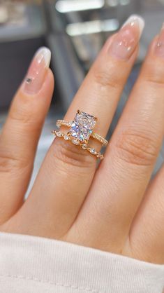 a close up of a person's hand with an engagement ring and wedding band