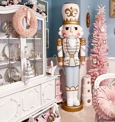 a large nutcracker standing next to a pink christmas tree in a living room