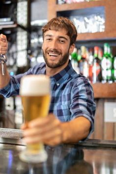 a man sitting at a bar with a glass of beer in his hand and smiling