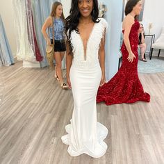 a woman standing in front of a mirror wearing a white dress