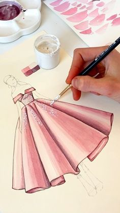 a person is drawing a dress on paper