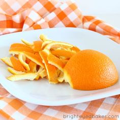 an orange cut in half on a white plate with checkered table cloth behind it