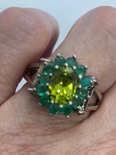 Rich and very bright green peridot ring surrounded by Emerald  Sterling silver  Size 8 can be sized by my jeweler. His service charge is $20  All rings are shipped in a nice gift box.   Check out our over a THOUSAND great reviews Engraving is $4 per letter and is not always perfect depending on the piece. It can take a few days if the jeweler is busy. This is payable to Paypal Judithsltd@gmail.com  PLEASE NOTE If we have multiples of the same vintage item, it is because we often purchase factory Oval Multi-stone Emerald Ring, Green Multi-stone Emerald Ring Fine Jewelry, Fine Jewelry Green Multi-stone Emerald Ring, Green Oval Cluster Ring Fine Jewelry, Emerald Cut Green Multi-stone Ring, Oval Green Gemstone Cluster Ring, Green Multi-stone Emerald Ring For May Birthstone, Green Multi-stone Emerald Rings, Green Cluster Ring With Halo Setting