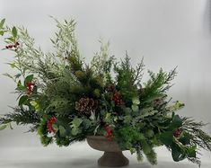 an arrangement of greenery and berries in a vase