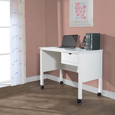 a white desk with a laptop on top of it in a pink walled office space