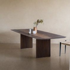 a wooden table with two chairs next to it and a potted plant on top