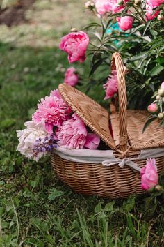 a wicker basket with pink flowers in the grass