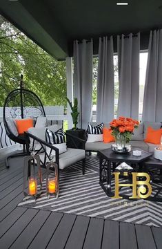 an outdoor living area with black and white furniture, orange pillows and candles on the coffee table