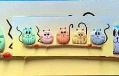 a group of cats sitting on top of a wooden shelf next to each other with faces painted on them