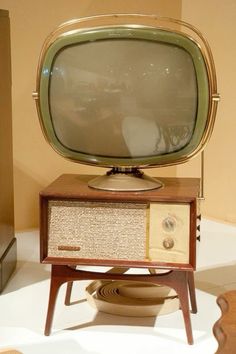 an old fashioned television sitting on top of a wooden stand