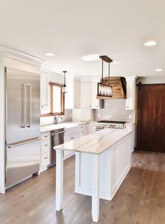 an empty kitchen with white cabinets and wood flooring on the wooden floor, along with stainless steel appliances