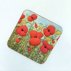 an image of a square coaster with red poppies and daisies painted on it