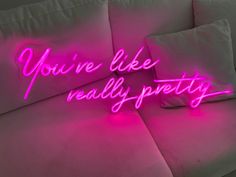 a pink neon sign that says you're like really pretty on the back of a couch