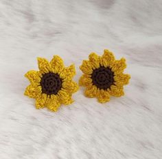 two crocheted sunflowers sitting on top of a white surface