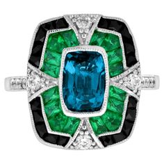 A striking and intriguing jewel, indeed. This bold and colorful Art Deco style ring highlights a gorgeous gleaming emerald cut London blue topaz framed in eye-catching contrast by French cut emerald and black onyx. Each side and shoulders set off with round diamond with milgrain edge. Ring Information Style: Edwardian Metal: 18K White Gold Weight: 6.50 g. (approx. total weight) Ring Size: US3-8 Center Gemstone Type: London Blue Topaz Shape: Octagon Size: 8 x 5.5 mm. Number: 1 Weight: 2.00 Carat Luxury Enamel Art Deco Rings, Luxury Blue Art Deco Rings, Vintage Emerald Rings Blue Nile, Gem Rings Stones 1stdibs, Edwardian Onyx Rings, Luxury Emerald Gemstones With Accent Stones, Luxury Emerald Cut Ring With Gemstone Accents, Luxury Multi-stone Emerald Cut Emerald Ring, Art Deco Topaz Ring With Center Stone