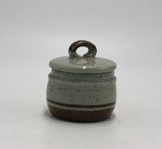 a white and brown ceramic container with a ring on the top sitting on a table