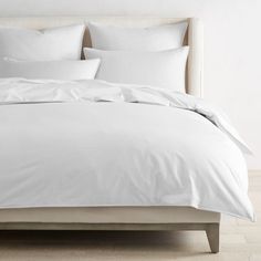 an unmade bed with white sheets and pillows