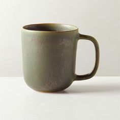 a green mug sitting on top of a white table