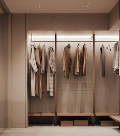 an open closet with clothes hanging on the wall and wooden benches in front of it